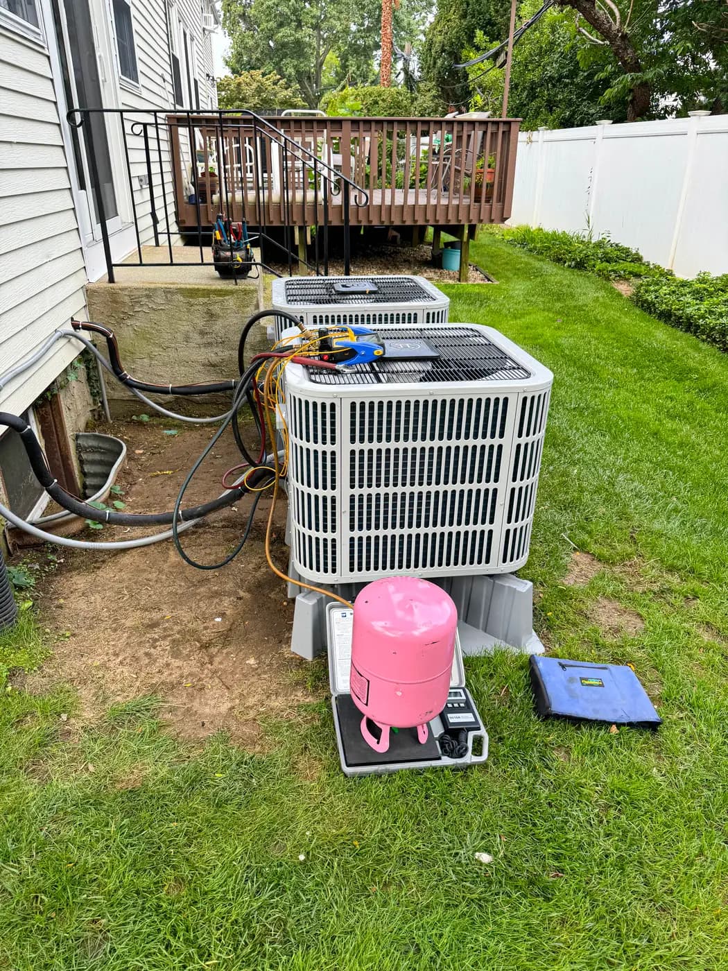 Condenser on lawn beside house with recovery tank and scale nearby