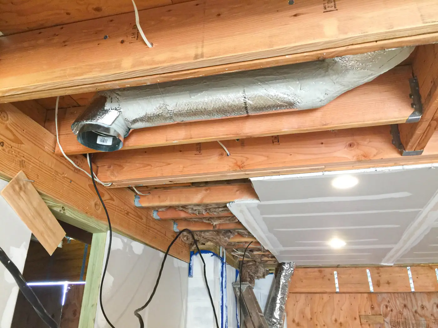 Insulated duct and wiring between floor joists in unfinished basement ceiling
