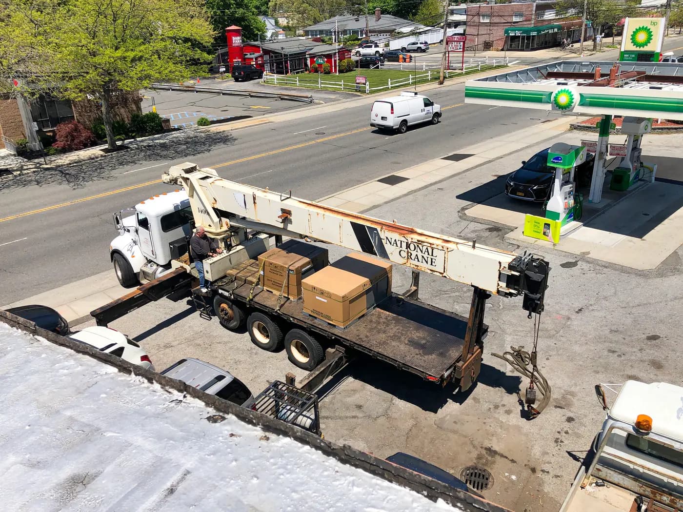 Boom crane truck parked at gas station seen from building roof