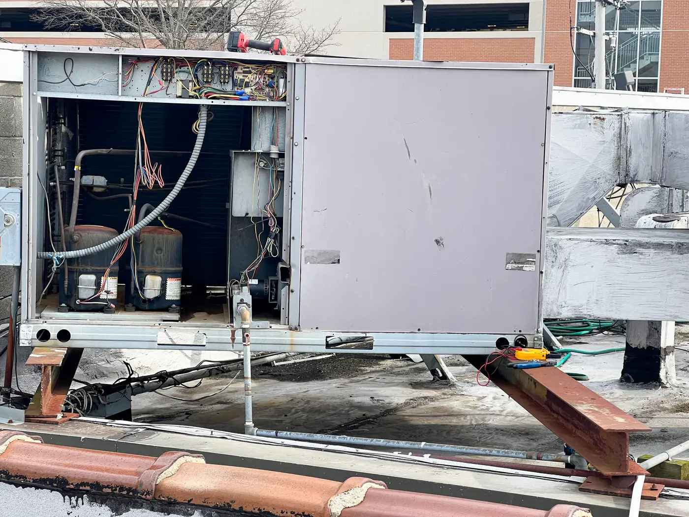 Rooftop unit with side panels removed exposing refrigerant piping on roof