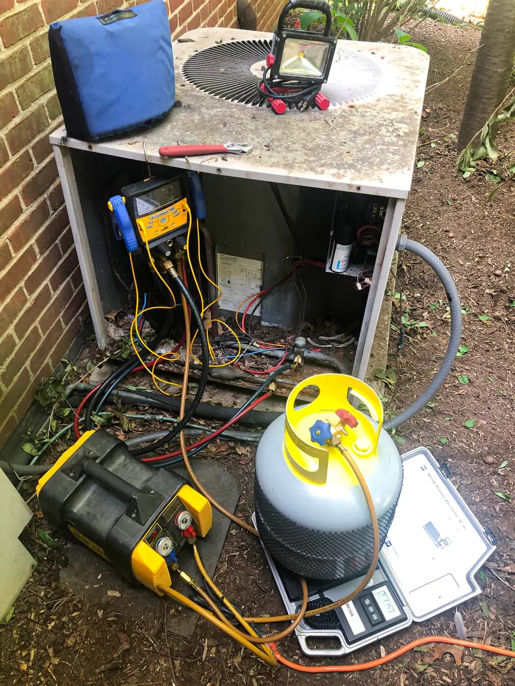 HVAC technician reading refrigerant pressures on a digital manifold gauge