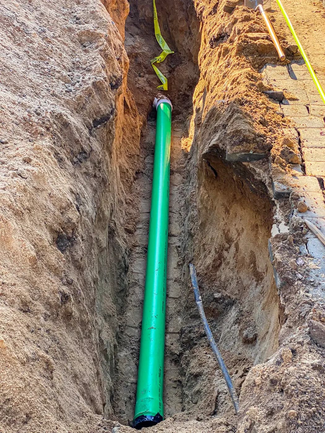 Green PVC sewer pipe laid in an open sand trench