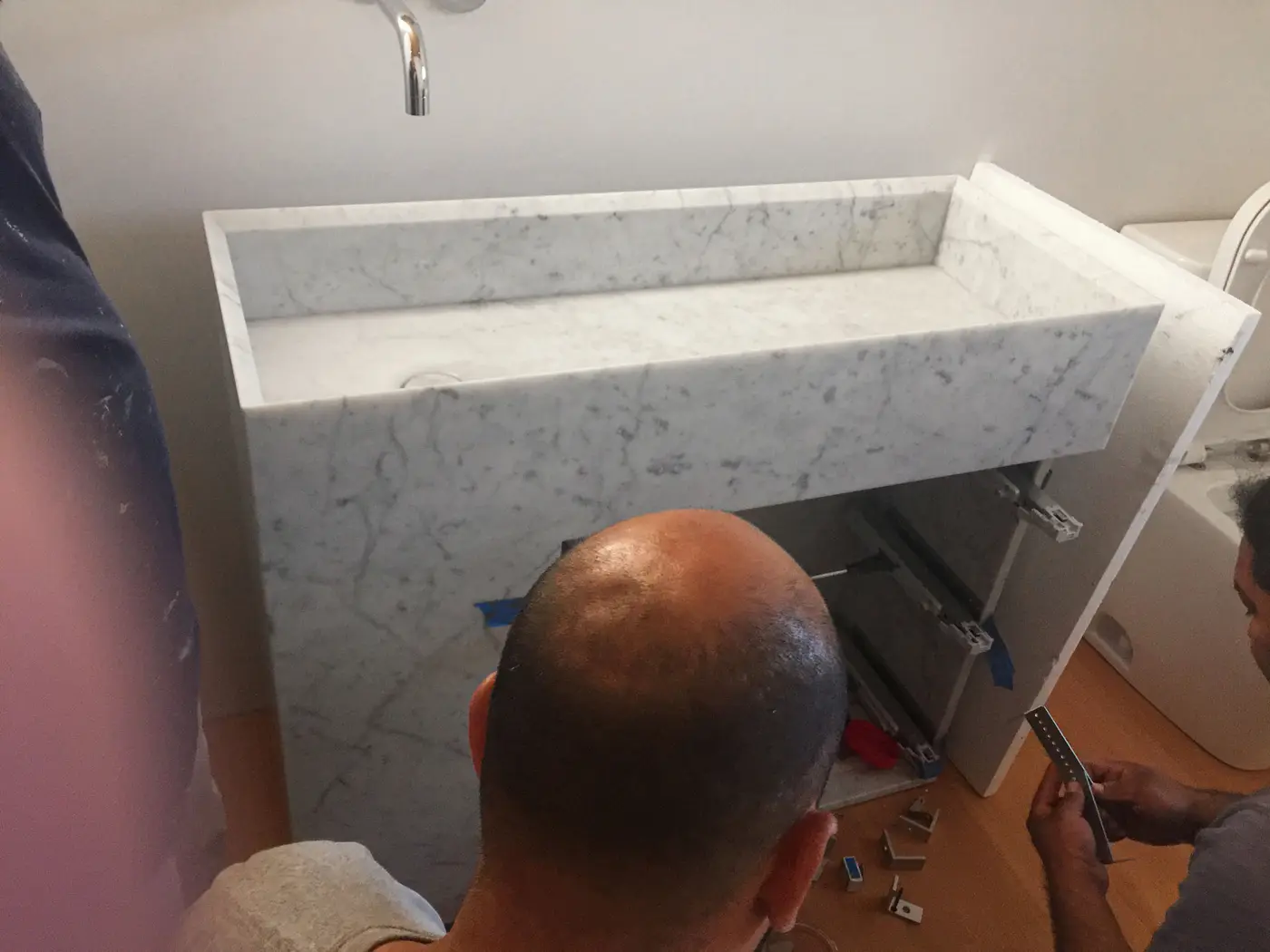 Installer fastening a stone vanity slab to a bathroom wall