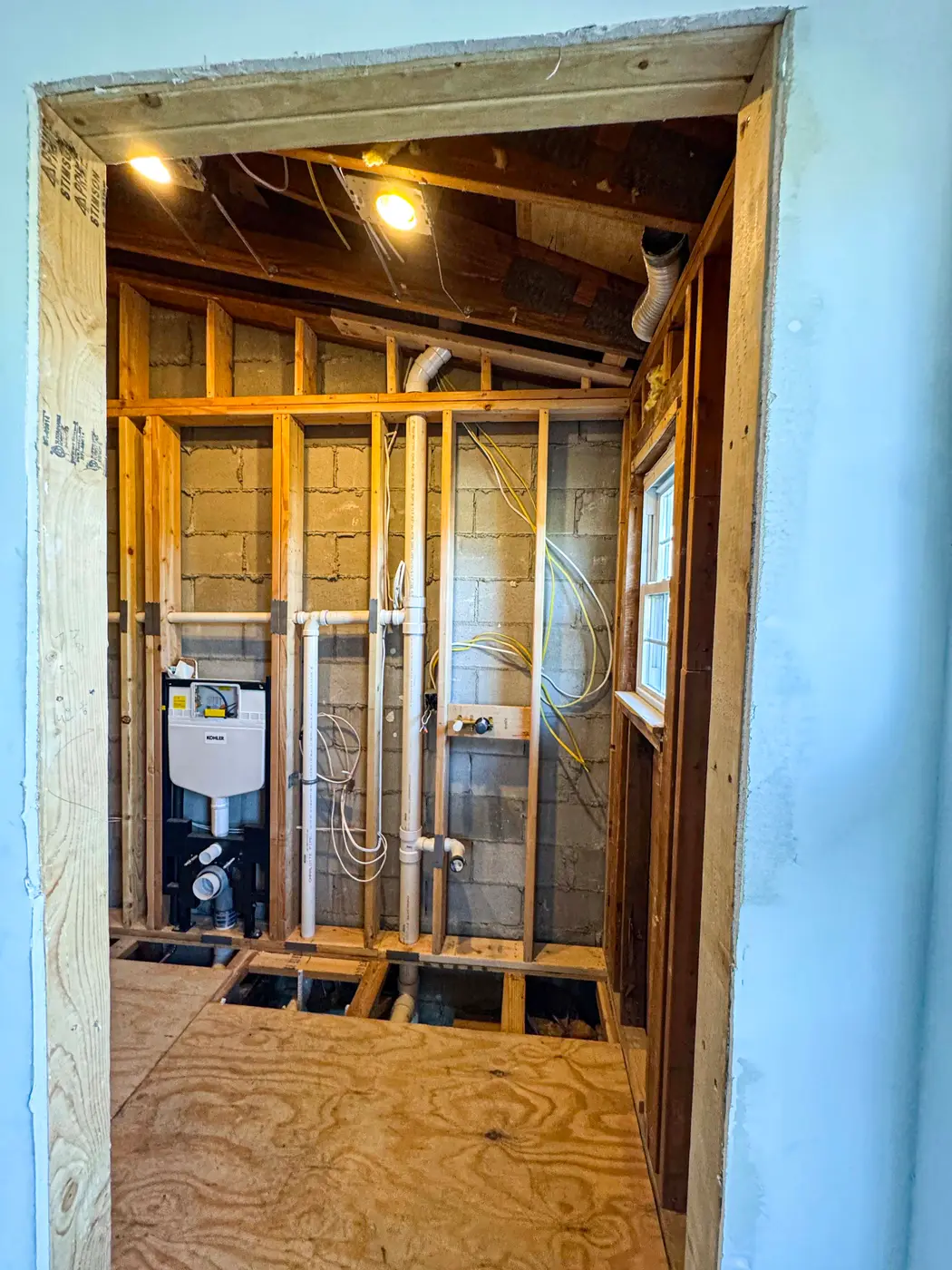 Doorway view into a framed basement bathroom rough-in