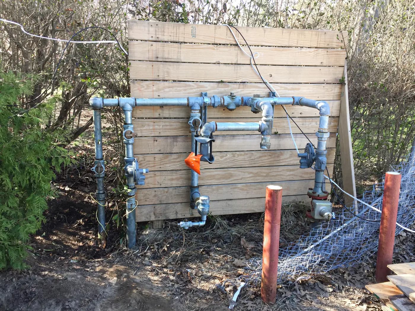 Galvanized pipe manifold with valves mounted on a wood fence