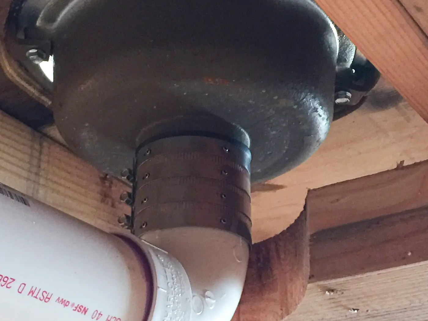 Cast iron closet bend and PVC drain hung under floor joists