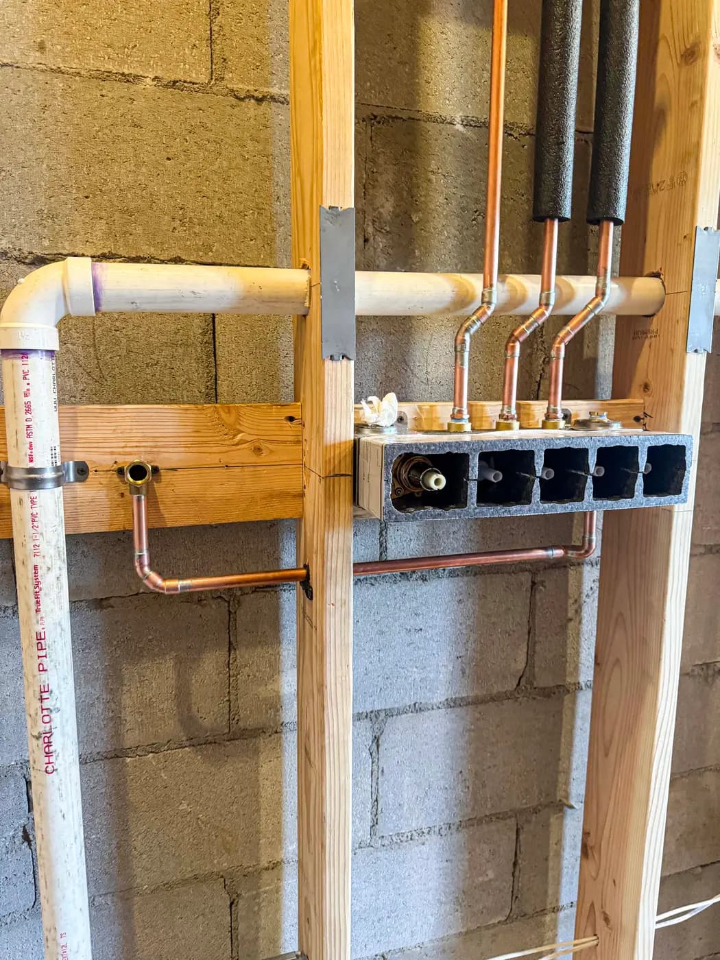 Copper manifold with capped stub-outs mounted on a block wall
