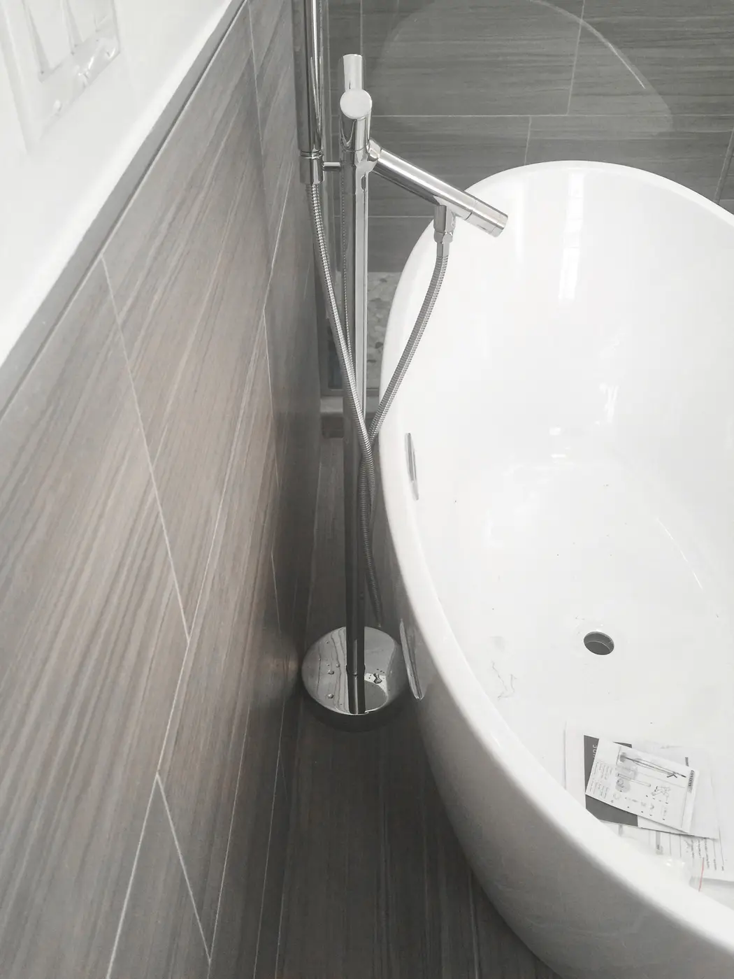 Freestanding tub with floor-mounted filler in a tiled bathroom