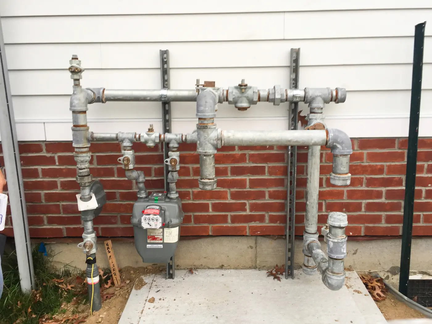 Galvanized gas manifold with multiple valves on a brick wall