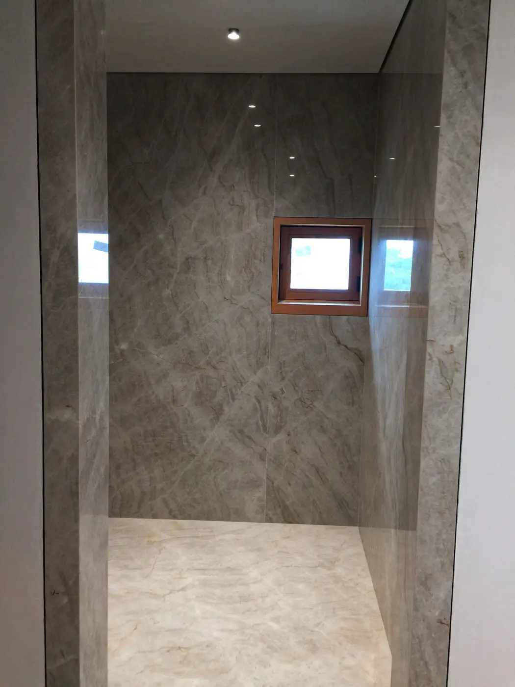 Finished walk-in shower with marble-look walls and small window