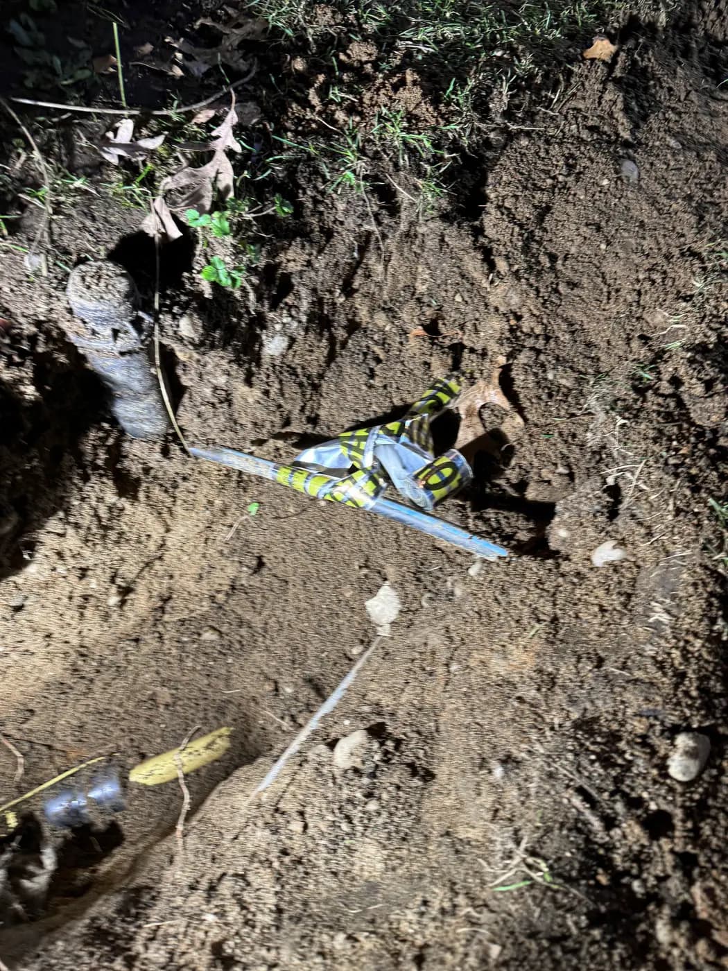 Open trench showing gray tracer line, yellow pipe and striped marker tape