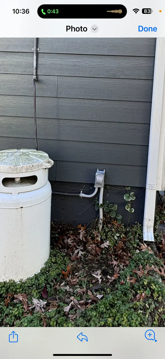 Phone screenshot of white cylindrical tank and metal riser beside gray siding