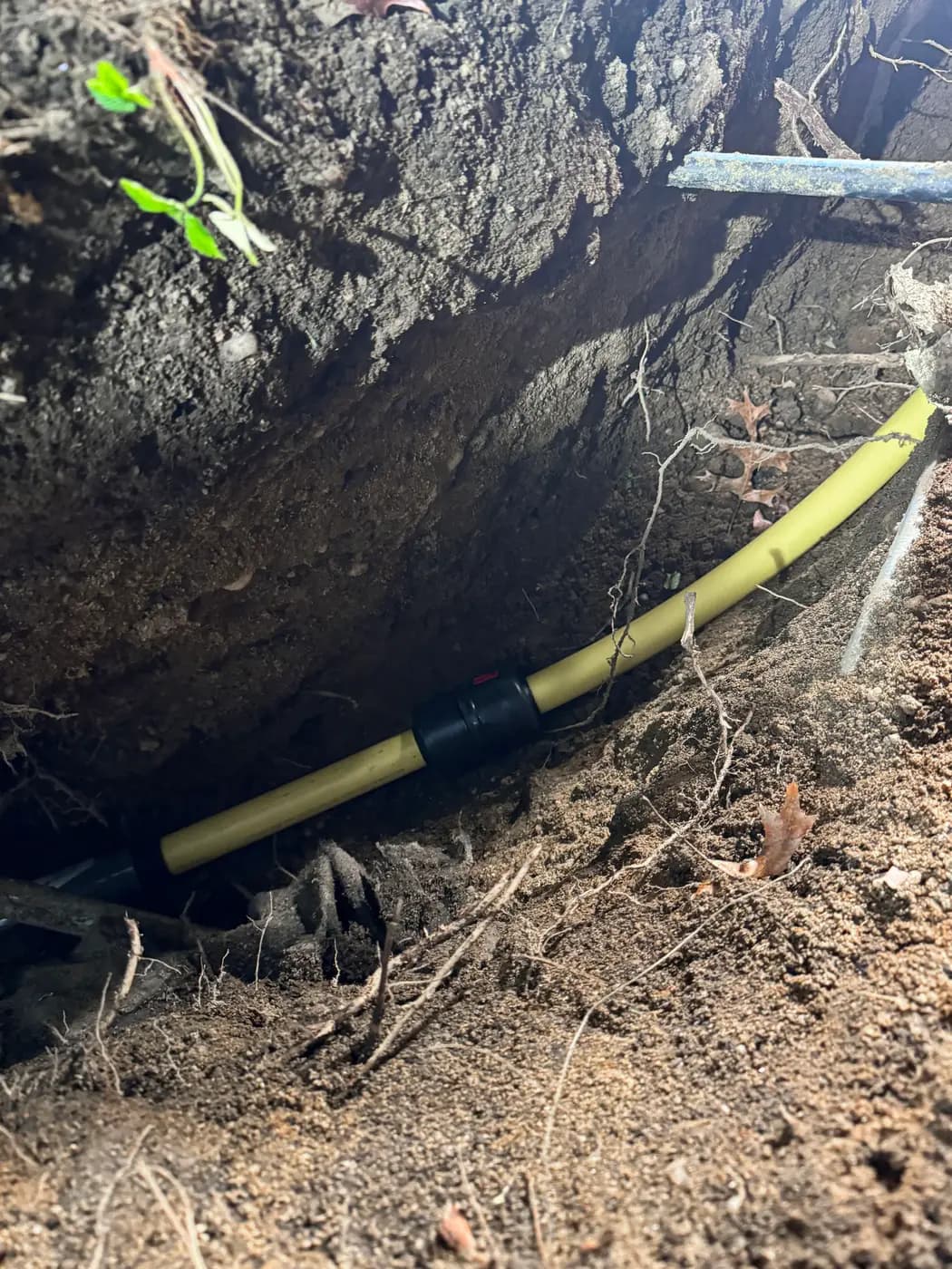 Yellow polyethylene gas pipe with black coupling resting in open trench