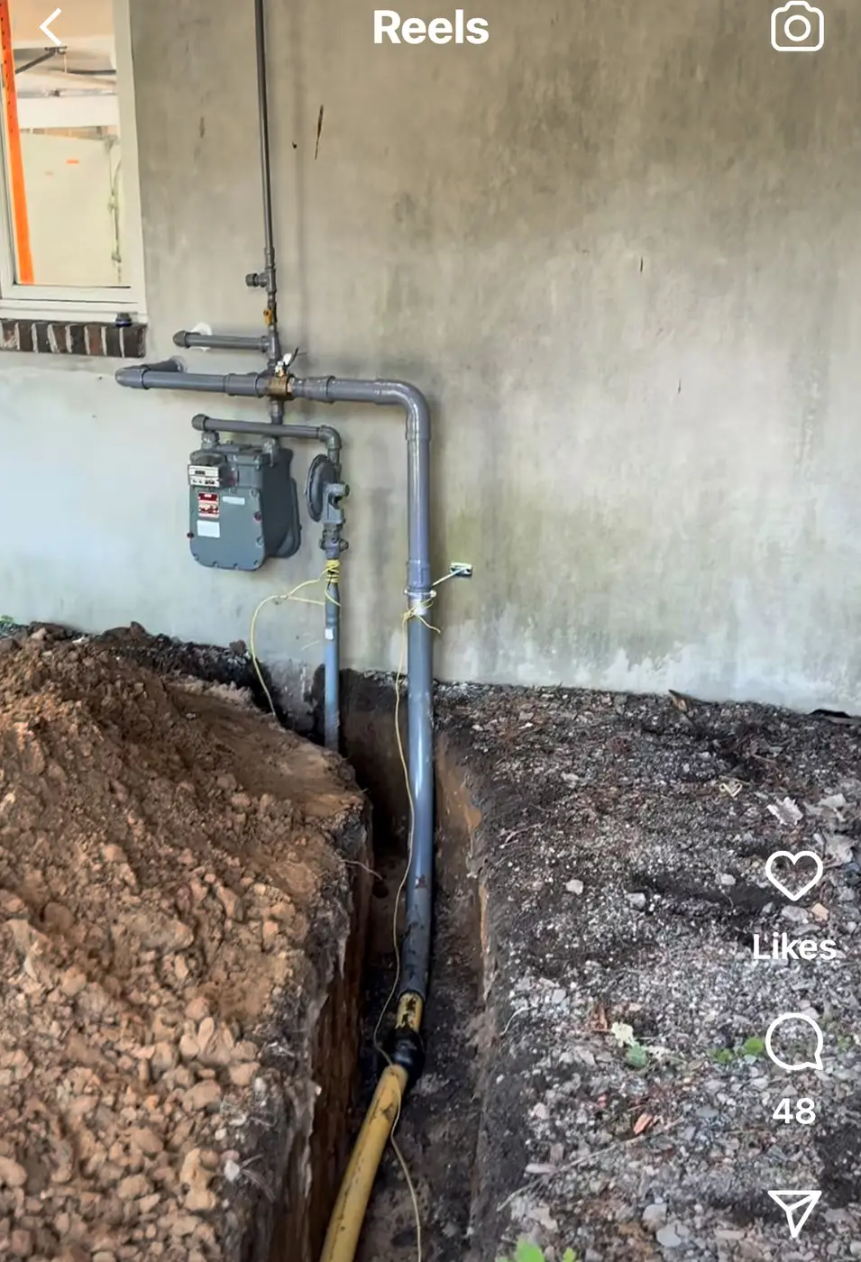 Social video still of trench beside stucco wall below gas meter and piping