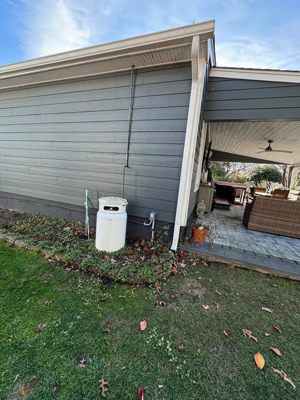 White cylindrical tank and riser piping on lawn beside house and patio