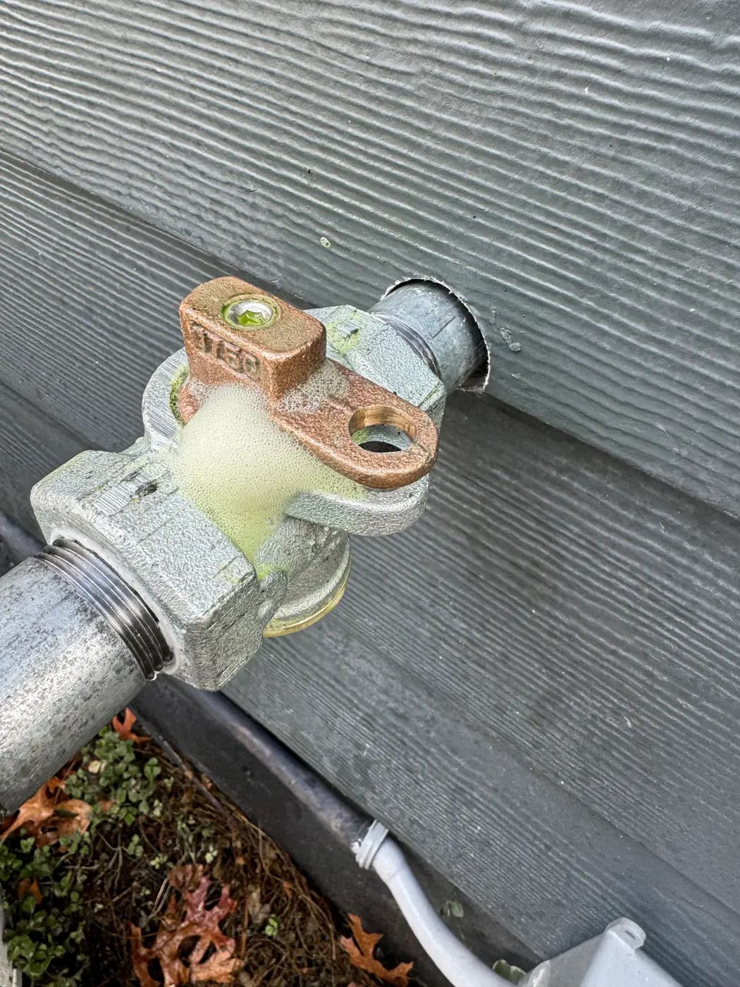 Close view of brass lockwing gas valve and threaded fitting at wall